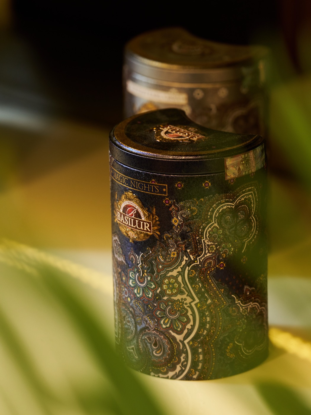 A Basilur Ceylon tea tin glowing among leaves
