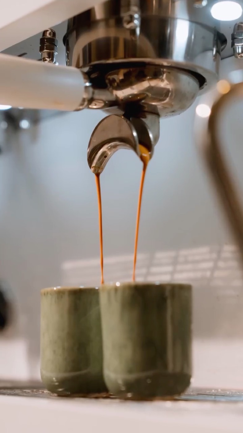 Espresso pouring from the portafilter into a green glass
